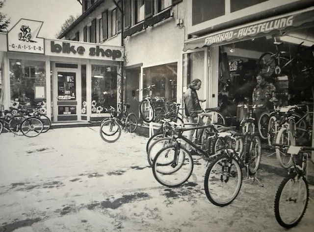 Historisches Schwarzwei&szlig;-Foto eines Fahrradgesch&auml;fts mit Fahrr&auml;dern vor der Fassade.
